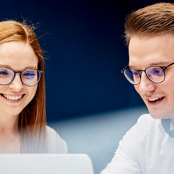 Junge Frau und junger Mann im Büro vor einem Laptop tauschen sich zu Business Process Management aus