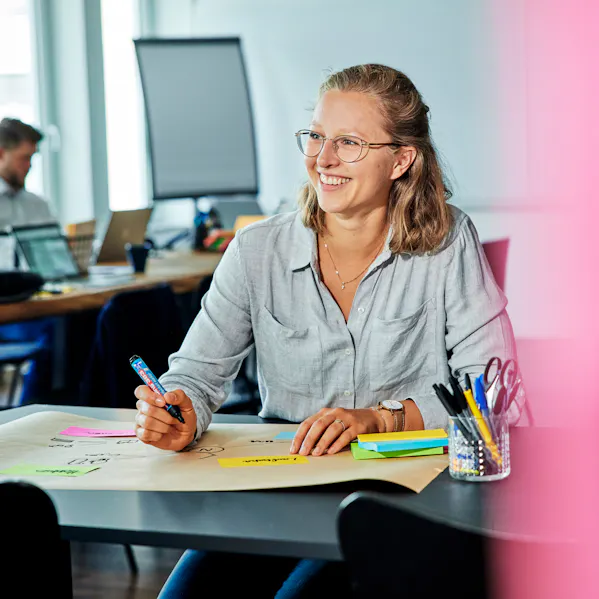 Eine Frau schreibt etwas auf und lacht dabei.