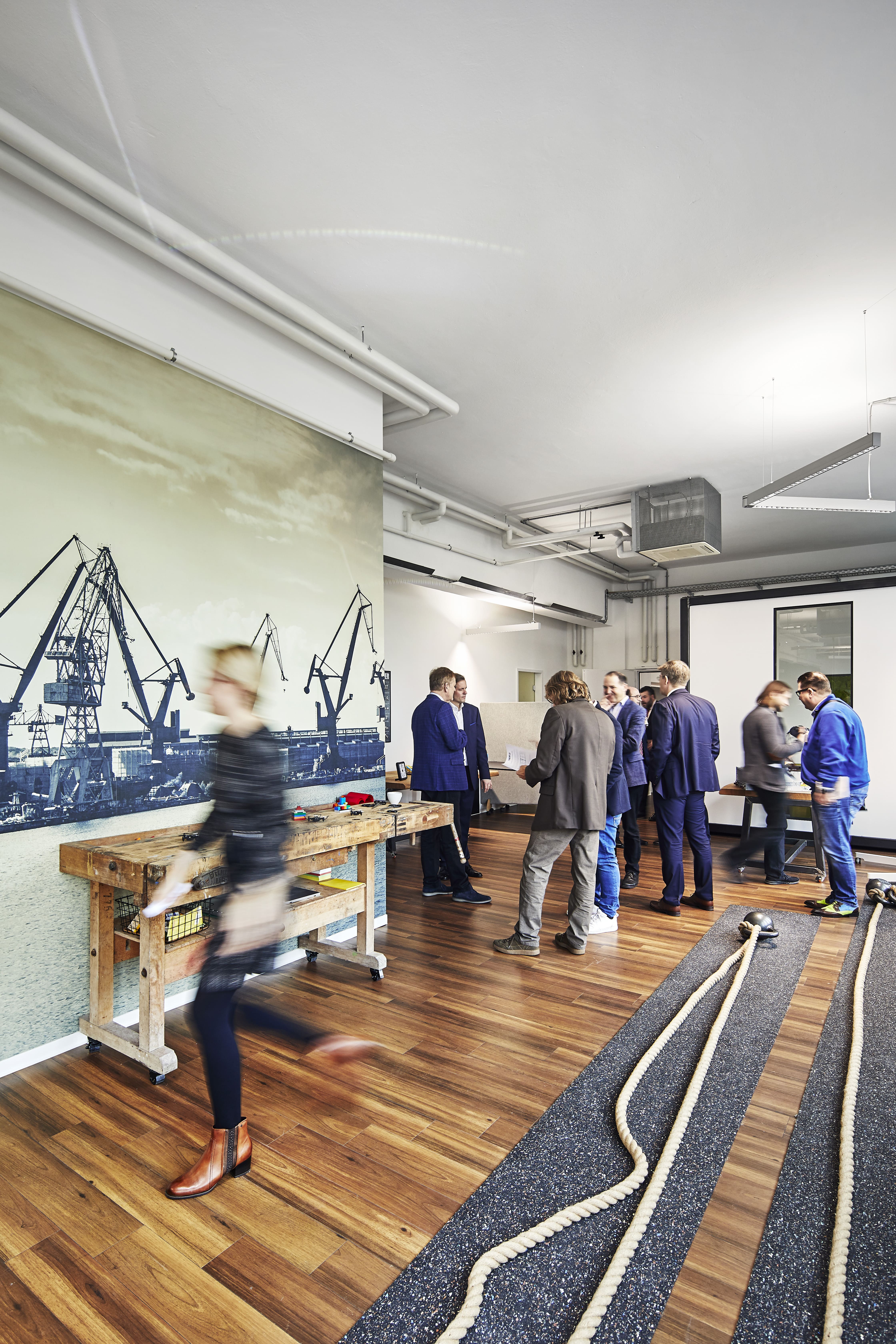 Mehrere Mitarbeiter stehen in einem informellen Kreis und tauschen Ideen aus, umgeben von einem kreativen Arbeitsumfeld.