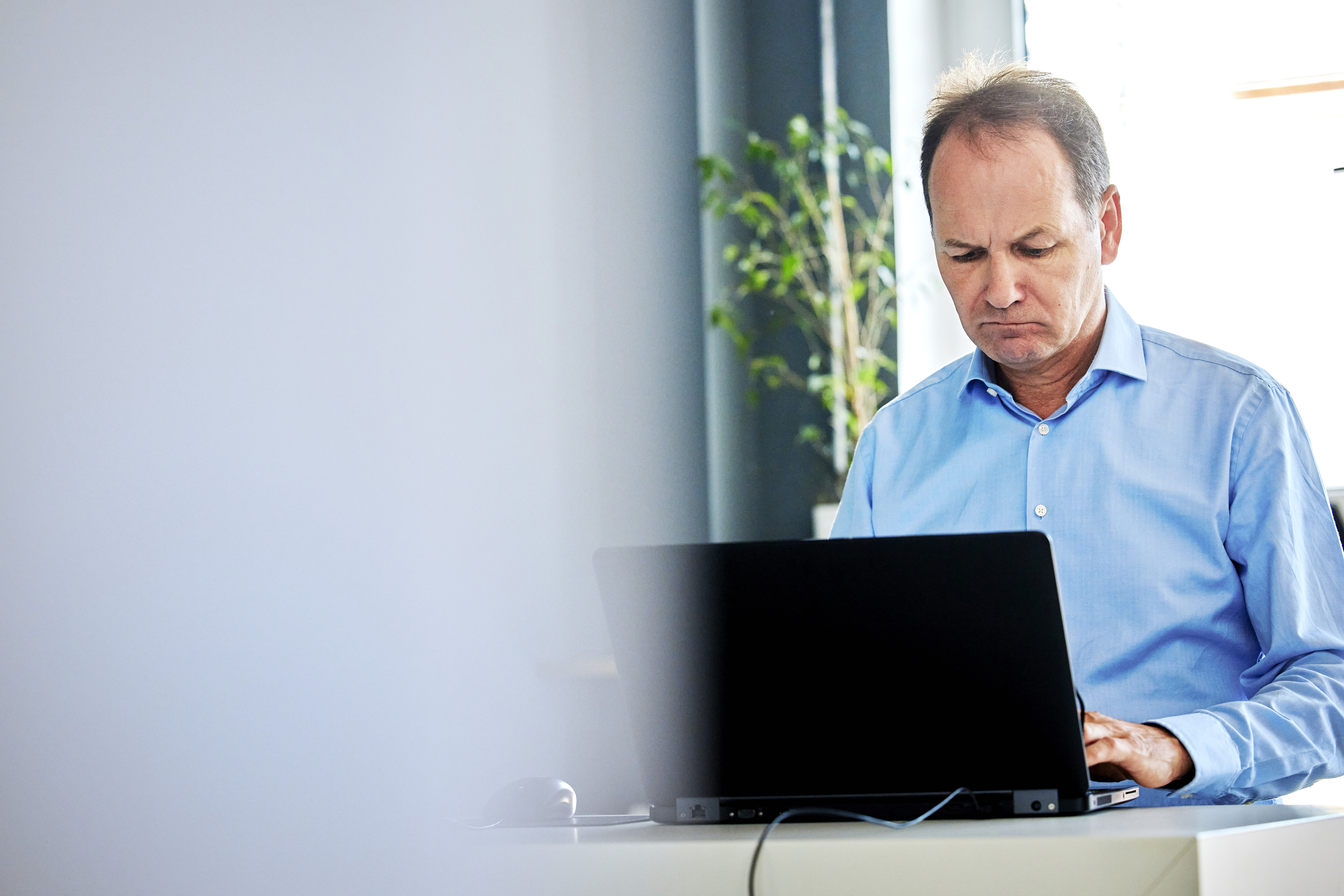 Ein Mann steht vor einem Laptop und schaut auf den Bildschirm
