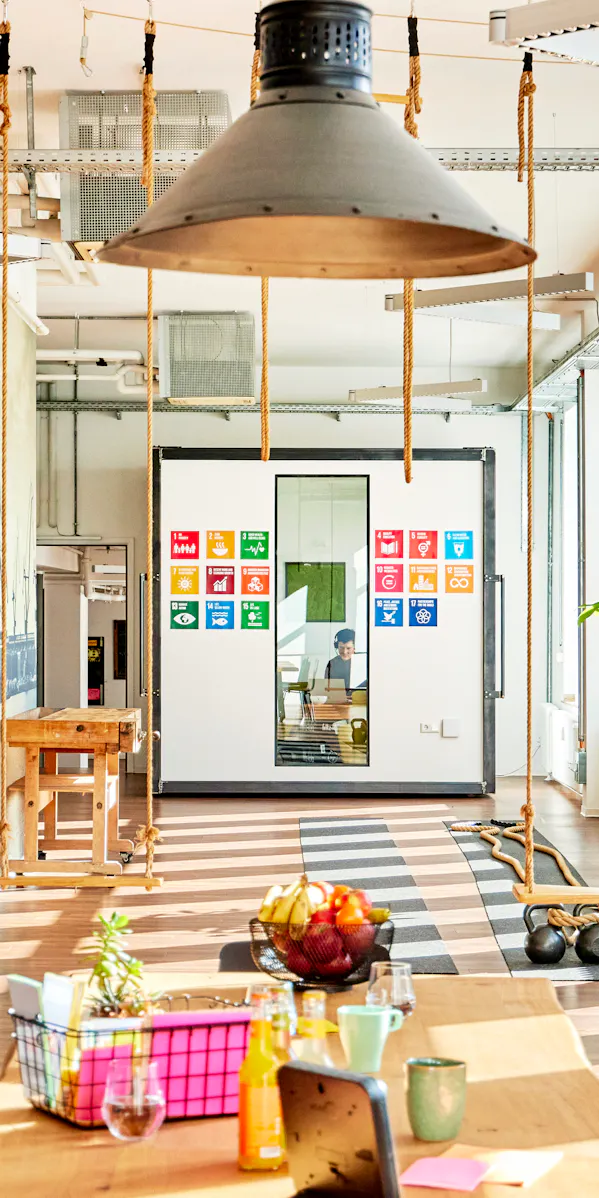 Ein inspirierender Arbeitsbereich mit einem kreativen Cube als Meetingraum. Die Wände des Cubes zeigen die 17 globalen Nachhaltigkeitsziele.