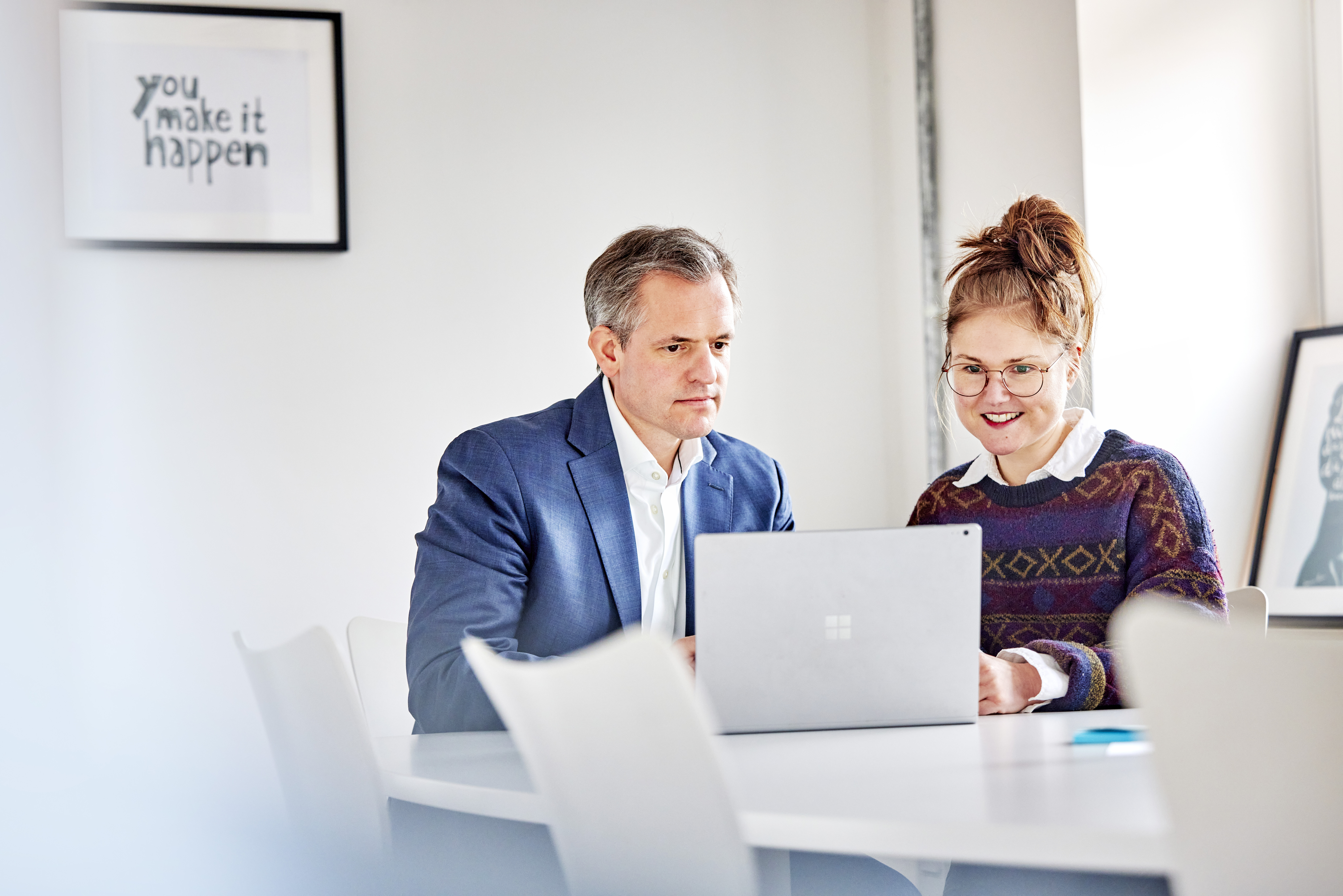 Teammitglieder vergleichen Informationen auf einem Laptop-Bildschirm.