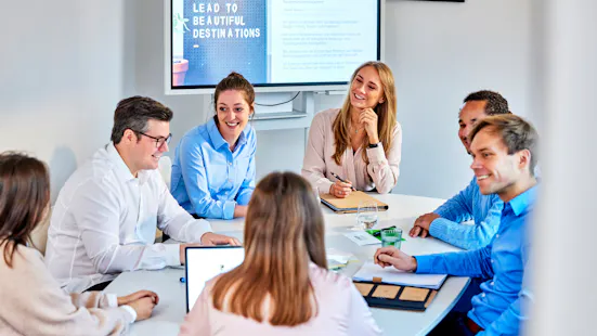 Gruppe von Mitarbeiter:innen sitzt an einem runden Tisch.