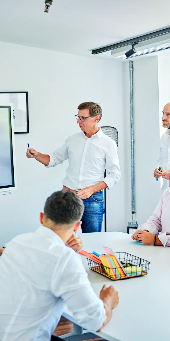 Six people in business attire take part in a playful rope challenge in a bright office while others clap and cheer — symbolizing teamwork and motivation.
